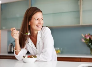 Woman smiling in a modern kitchen while preparing healthy food.