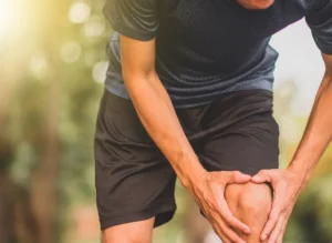 Person holding their knee due to joint pain before regenerative treatment.