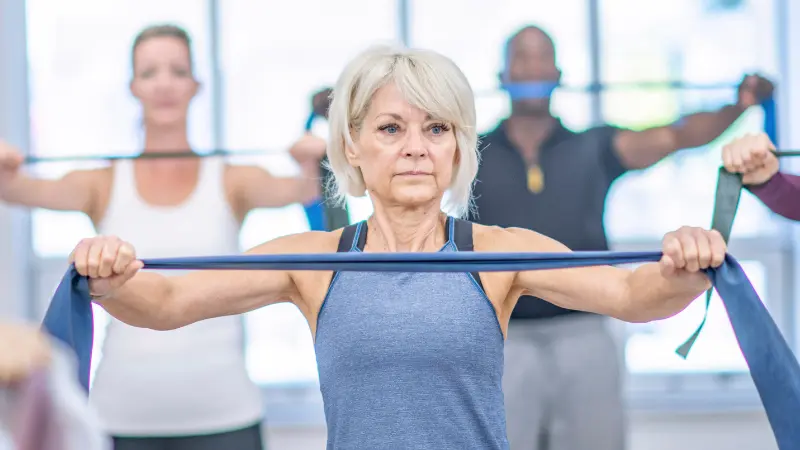 Older adults performing resistance band strength training in a gym setting to support muscle mass and healthy aging.
