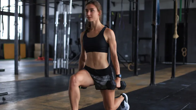 Person performing weighted lunges to build lower-body muscle mass for strength and healthy aging.