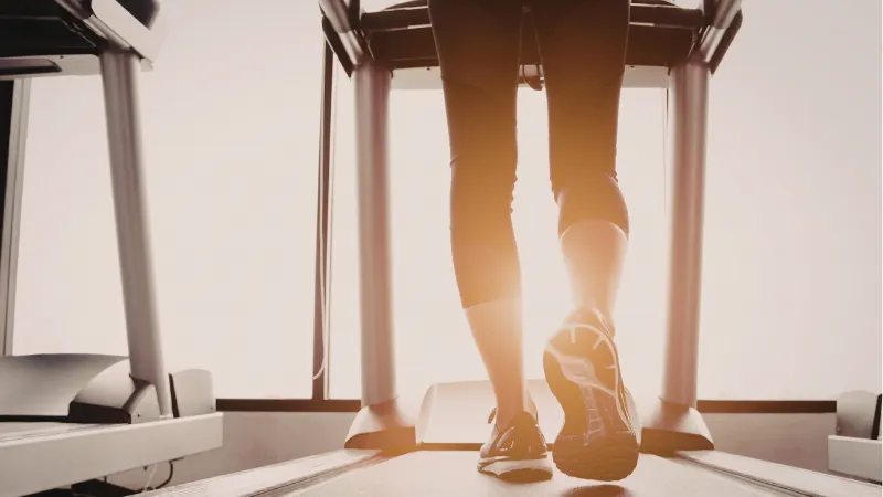 Individual walking on treadmill during VO₂ max testing to assess cardiovascular fitness and longevity performance.