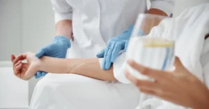 Close-up of patient arm receiving IV therapy with medical professional wearing gloves in a clinical environment