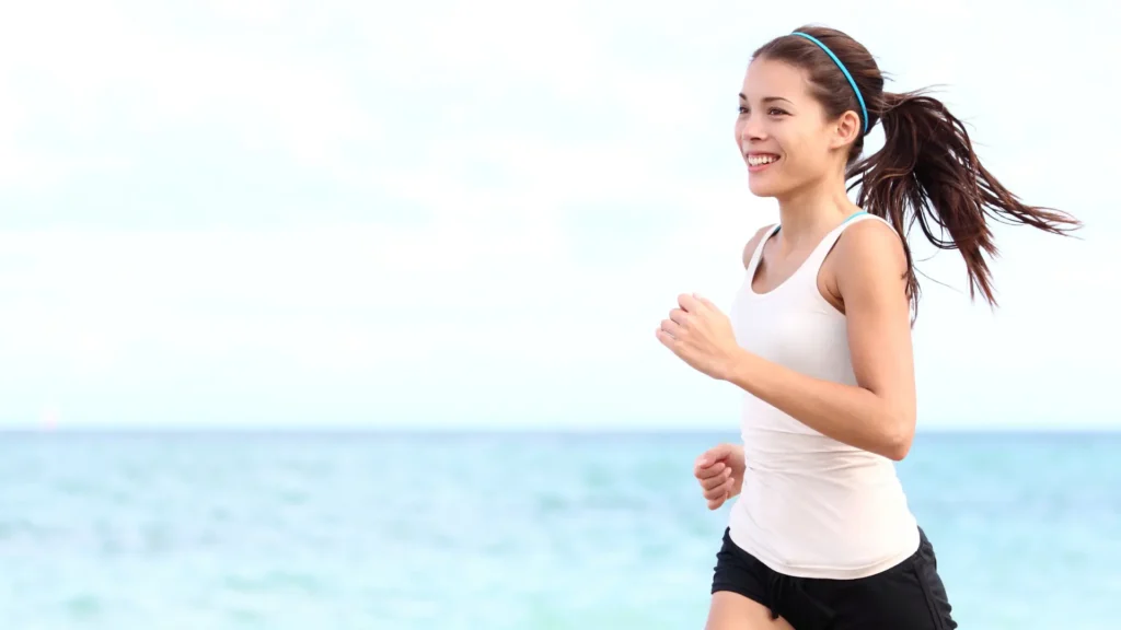 Woman running along the beach representing healthy lifestyle and reduced chronic inflammation