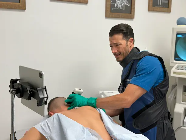 Dr. hoz using ultrasound to evaluate injured areas in patients neck and back